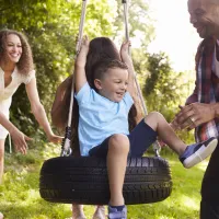 Family of four playing on a tire swing together